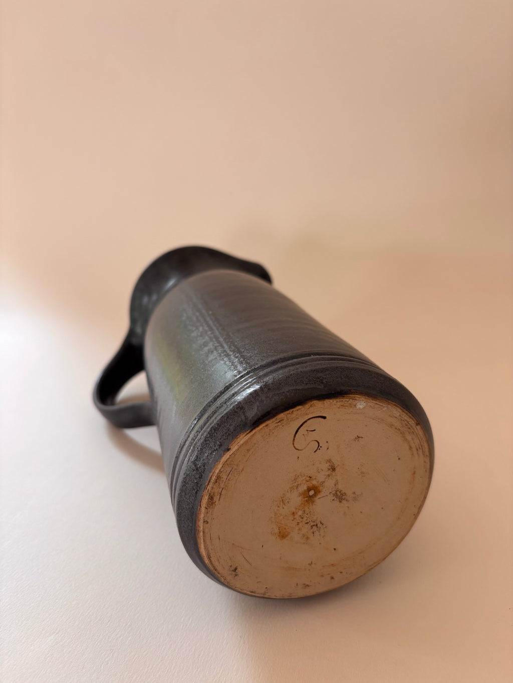 underside of a vintage stoneware jug showing artist signature inscribed in clay