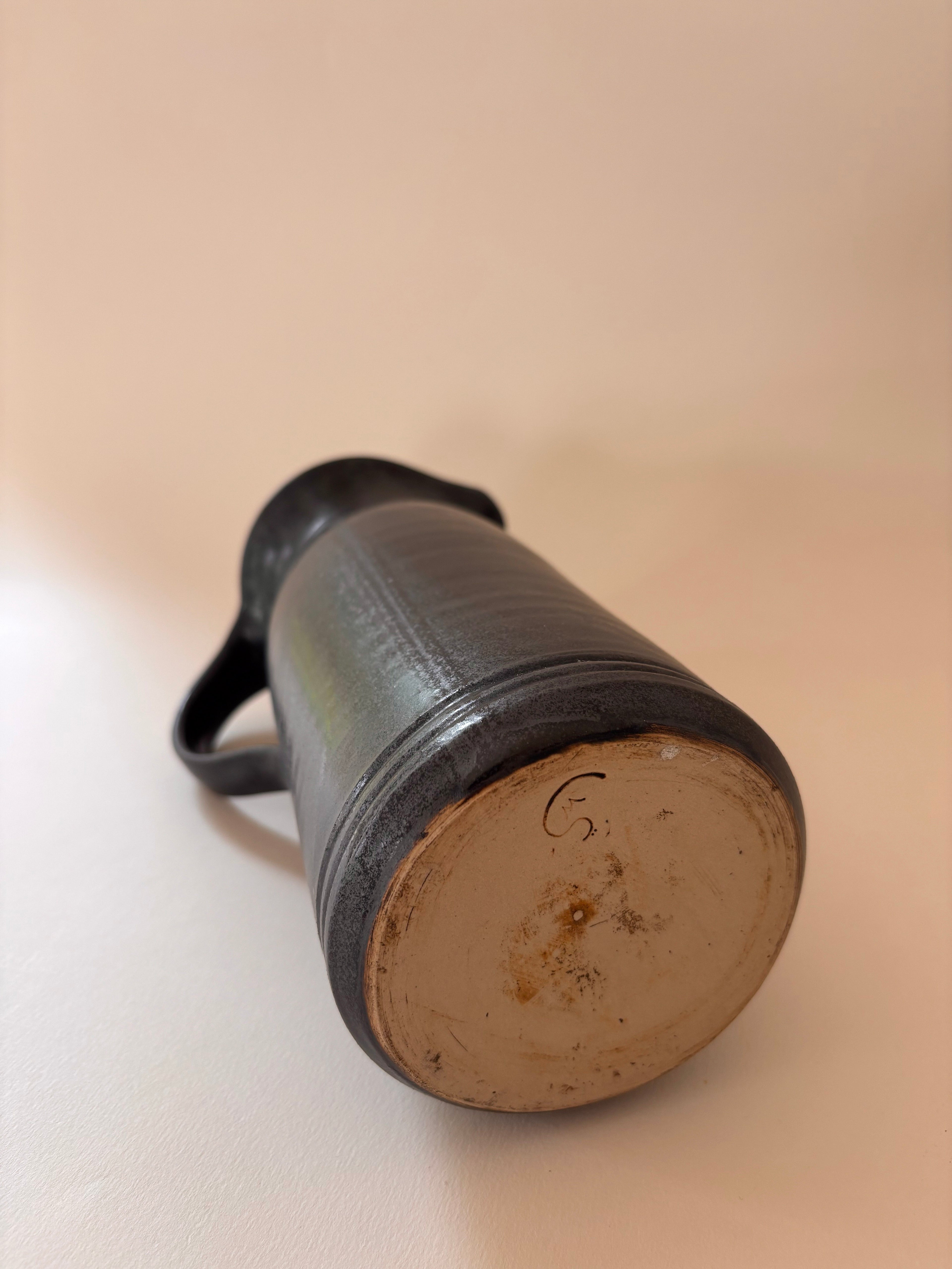 underside of a vintage stoneware jug showing artist signature inscribed in clay