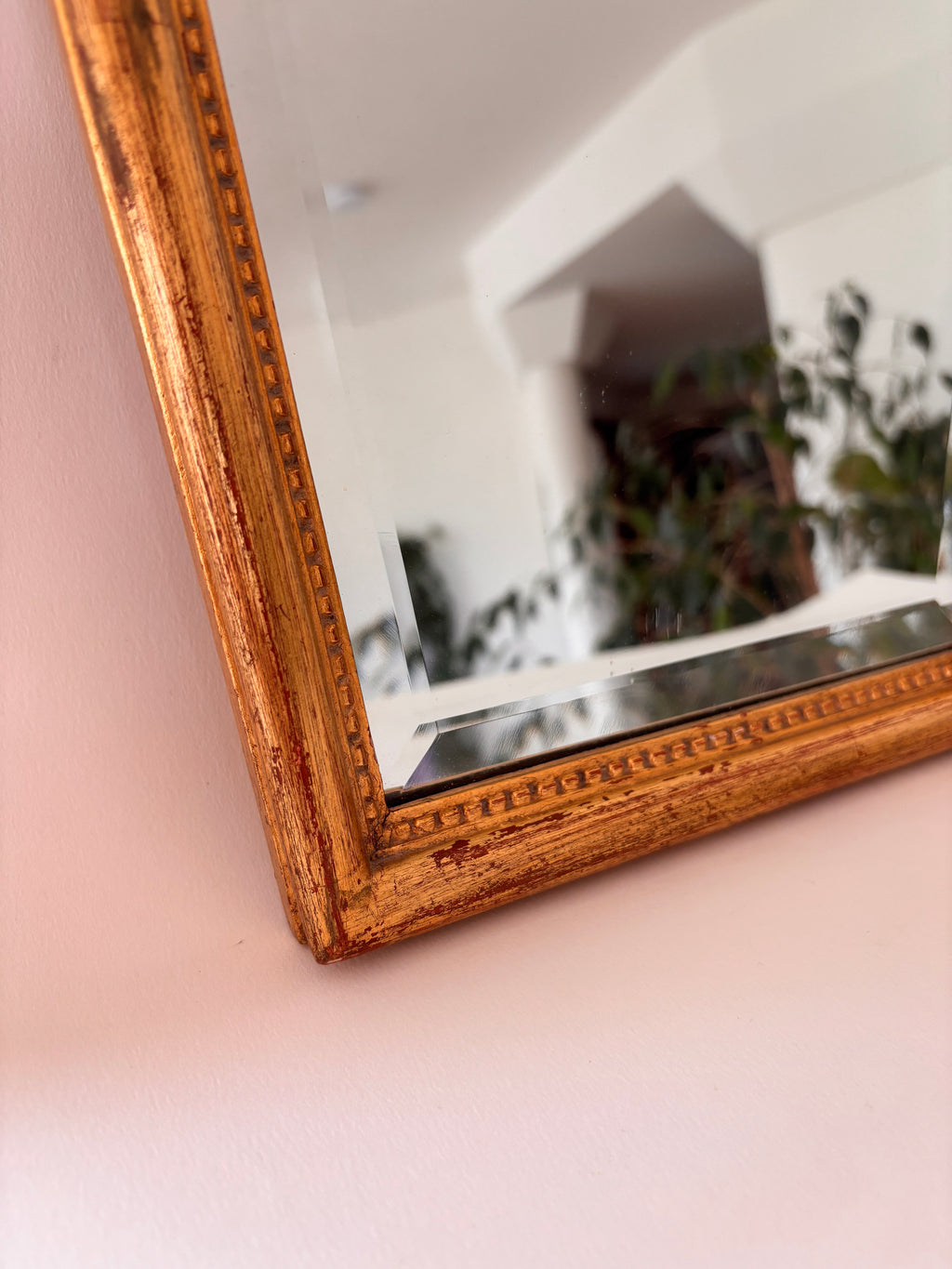 Close-up of gold frame and beaded edge detail on a vintage arched wall mirror