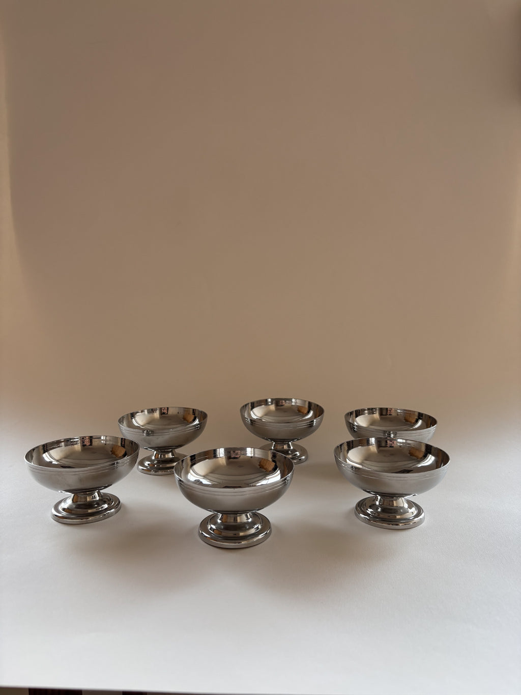 Set of six vintage stainless steel dessert cups by L'Étang & Rémy arranged on a neutral surface