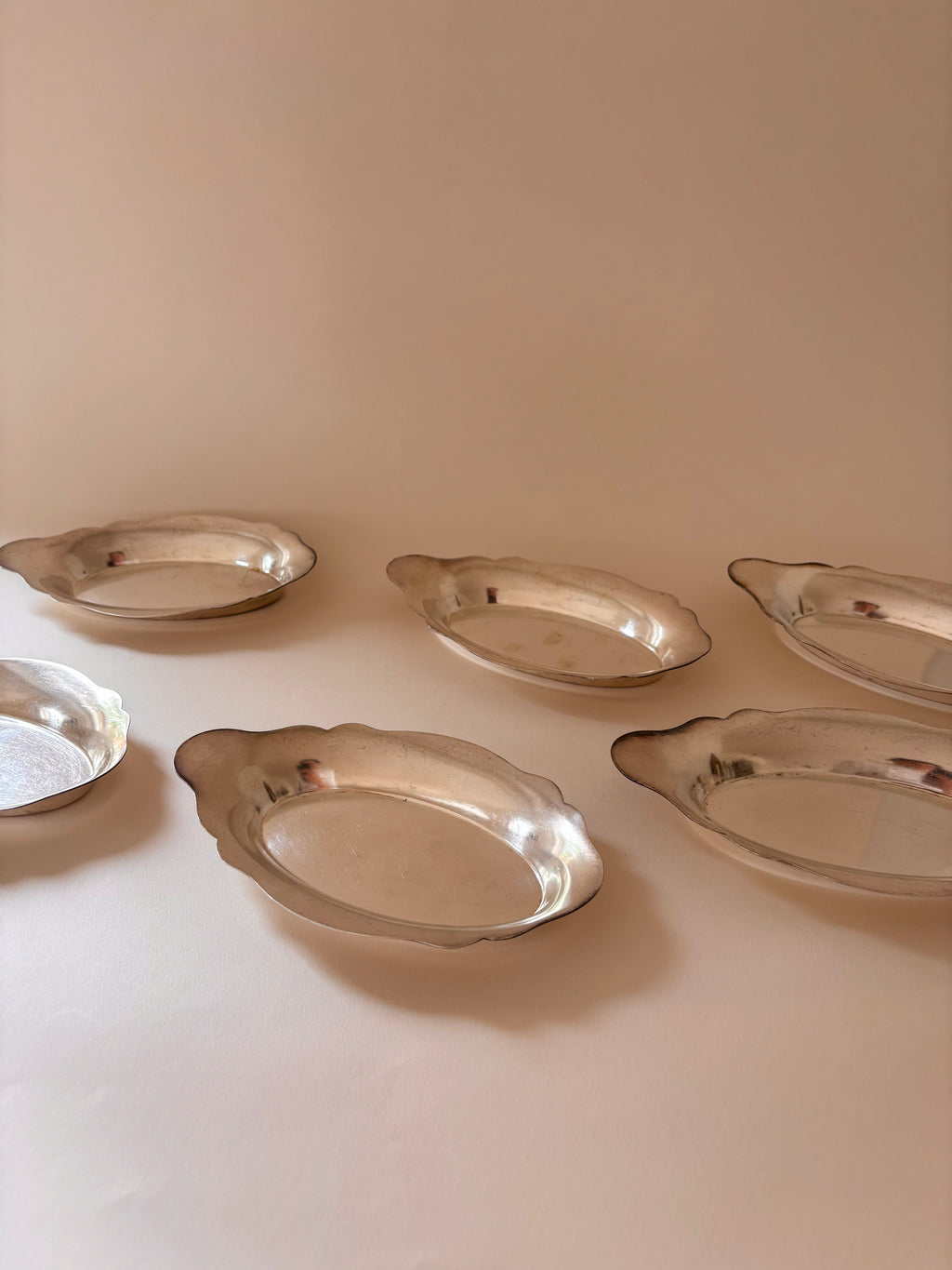 Vintage silver-plated oval dishes with scalloped edges front view.