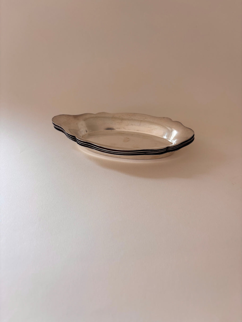 Vintage silver-plated oval dishes stacked together.