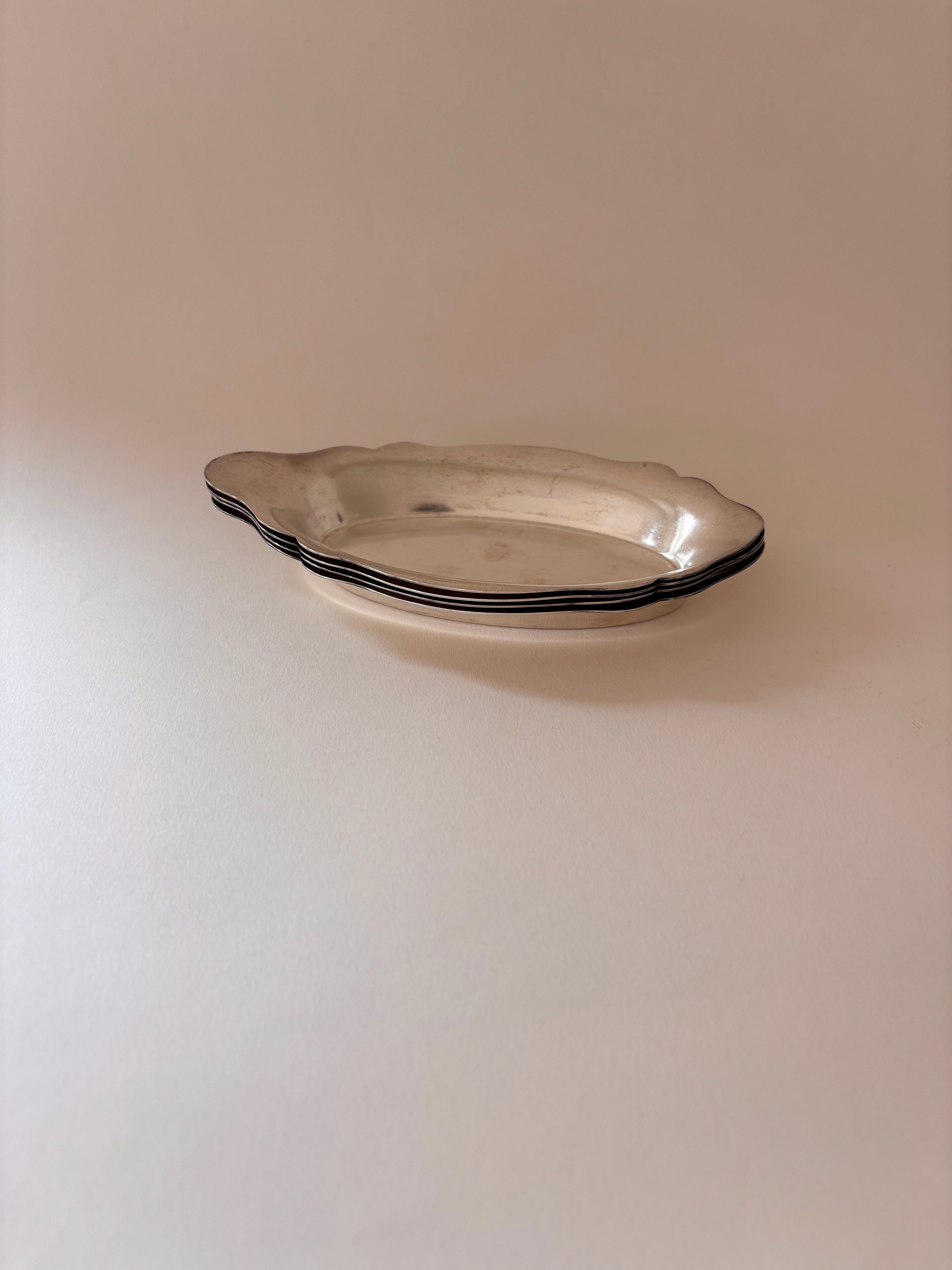 Vintage silver-plated oval dishes stacked together.