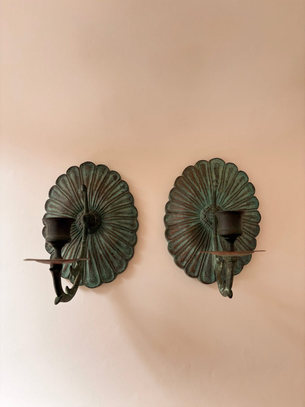 vintage brass wall candle sconce with verdigris patina and scalloped fluted backplate on a white wall