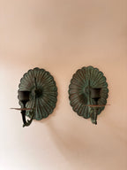vintage brass wall candle sconce with verdigris patina and scalloped fluted backplate on a white wall