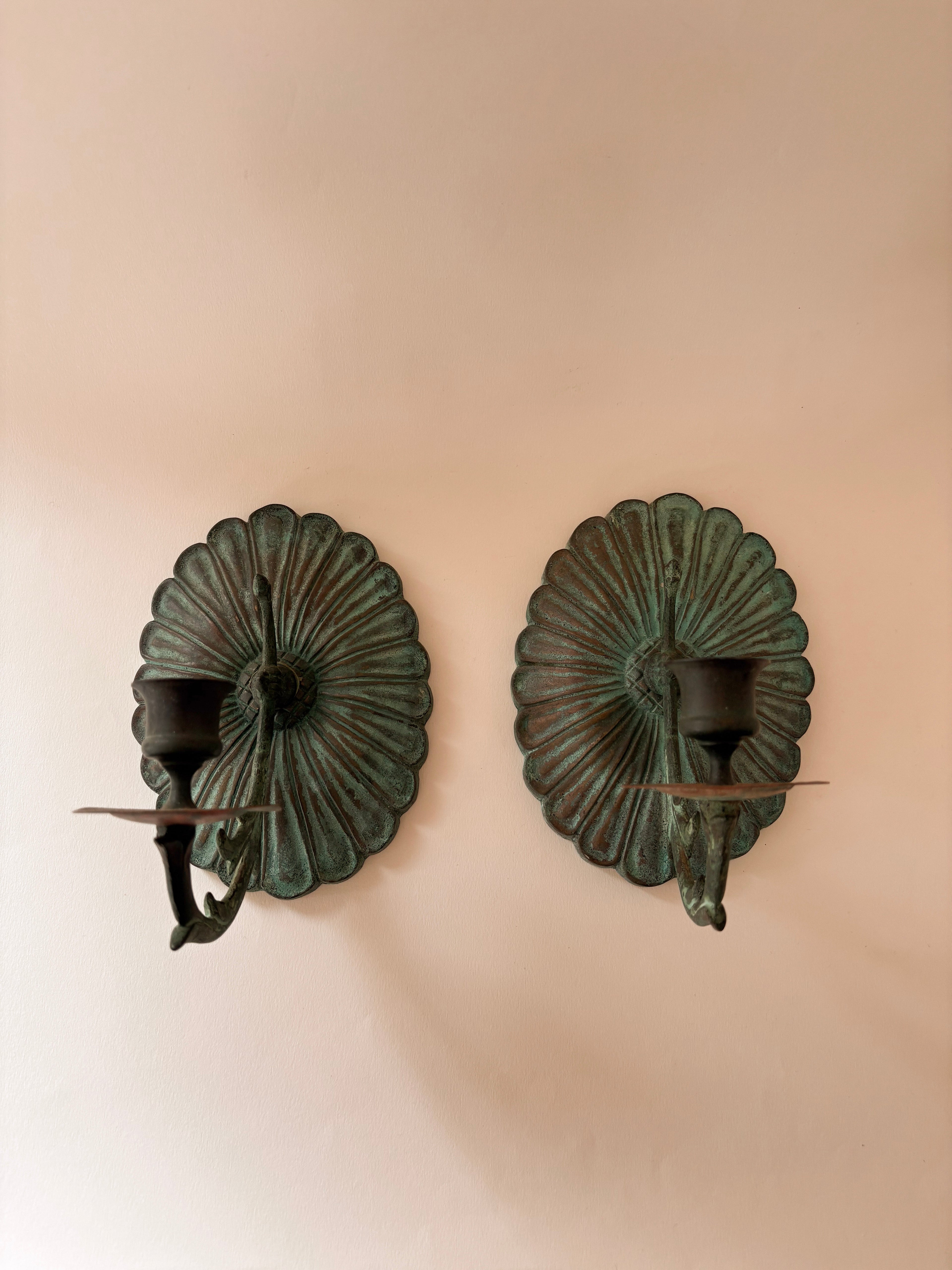 vintage brass wall candle sconce with verdigris patina and scalloped fluted backplate on a white wall