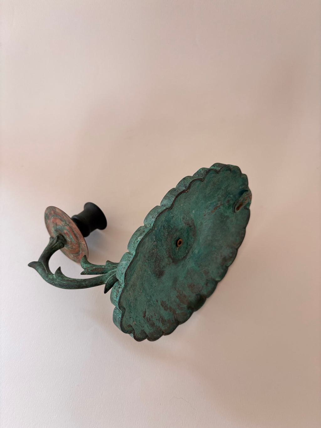 Back of a vintage brass candle candle sconce showing mounting detail and patina