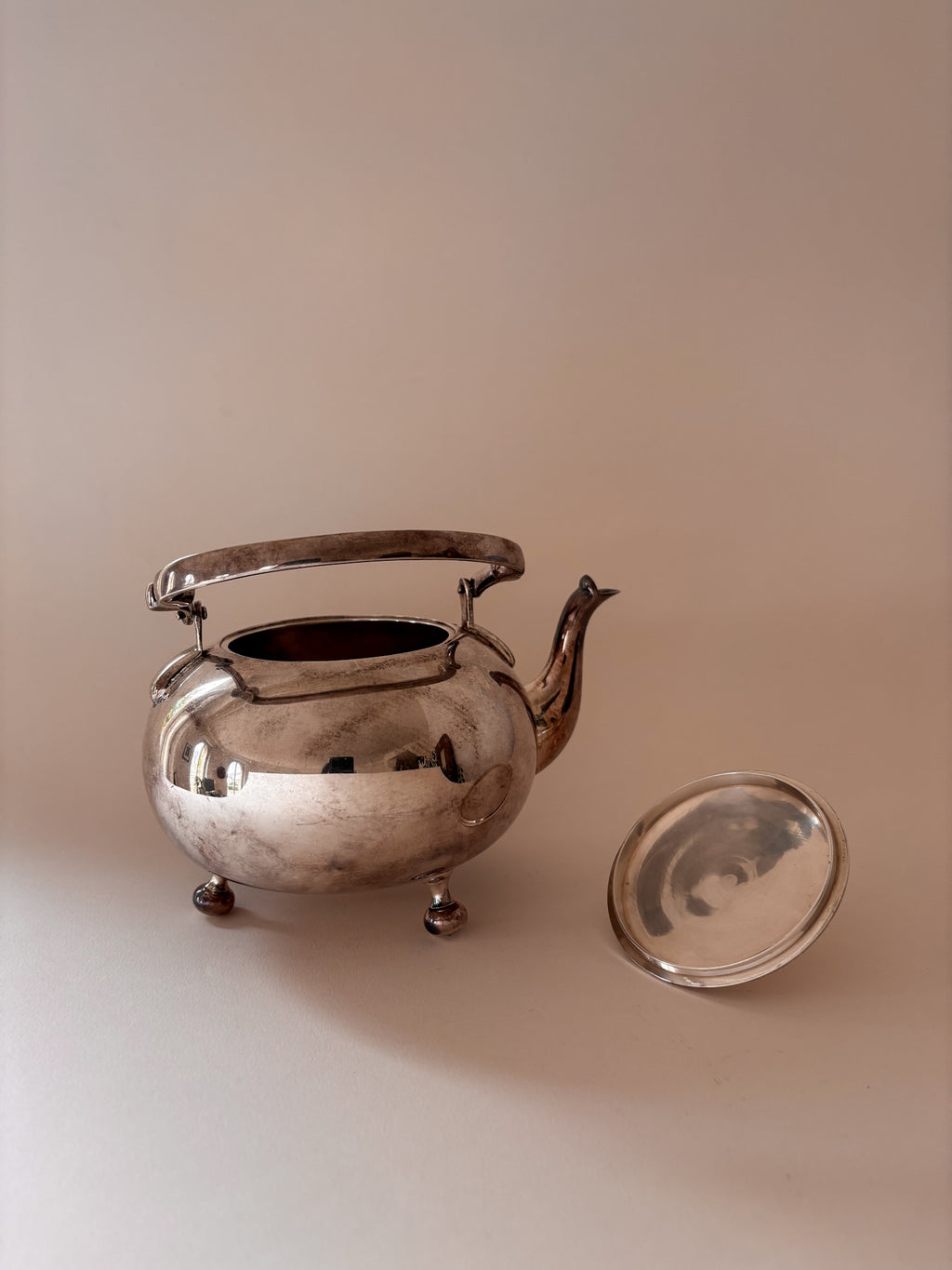 front view of a vintage silver-plated teapot showing handle, lid and oxidation