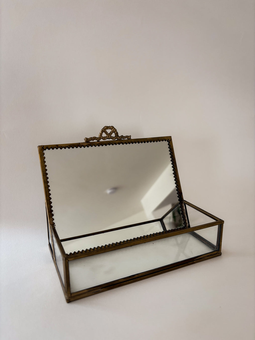 Front view of vintage brass and glass vanity box with ornamental detailing