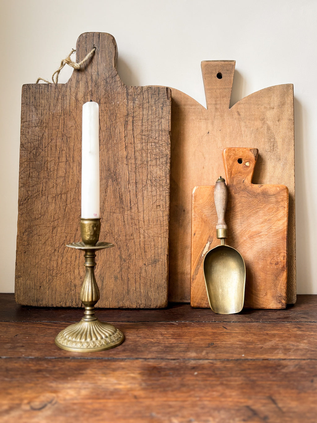 Three wooden cutting boards and a brass candlestick 