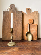 Three wooden cutting boards and a brass candlestick 