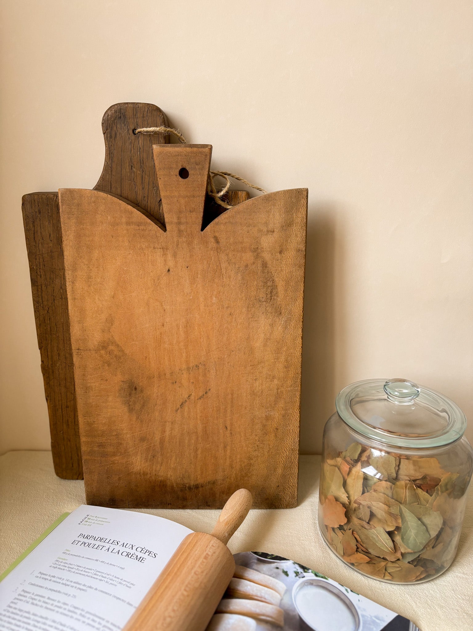 Wooden cutting board, rolling pin, and jar on a surface with a neutral background