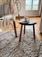 Cozy living room with a vintage french wooden stool, and coffee cup on a rug.