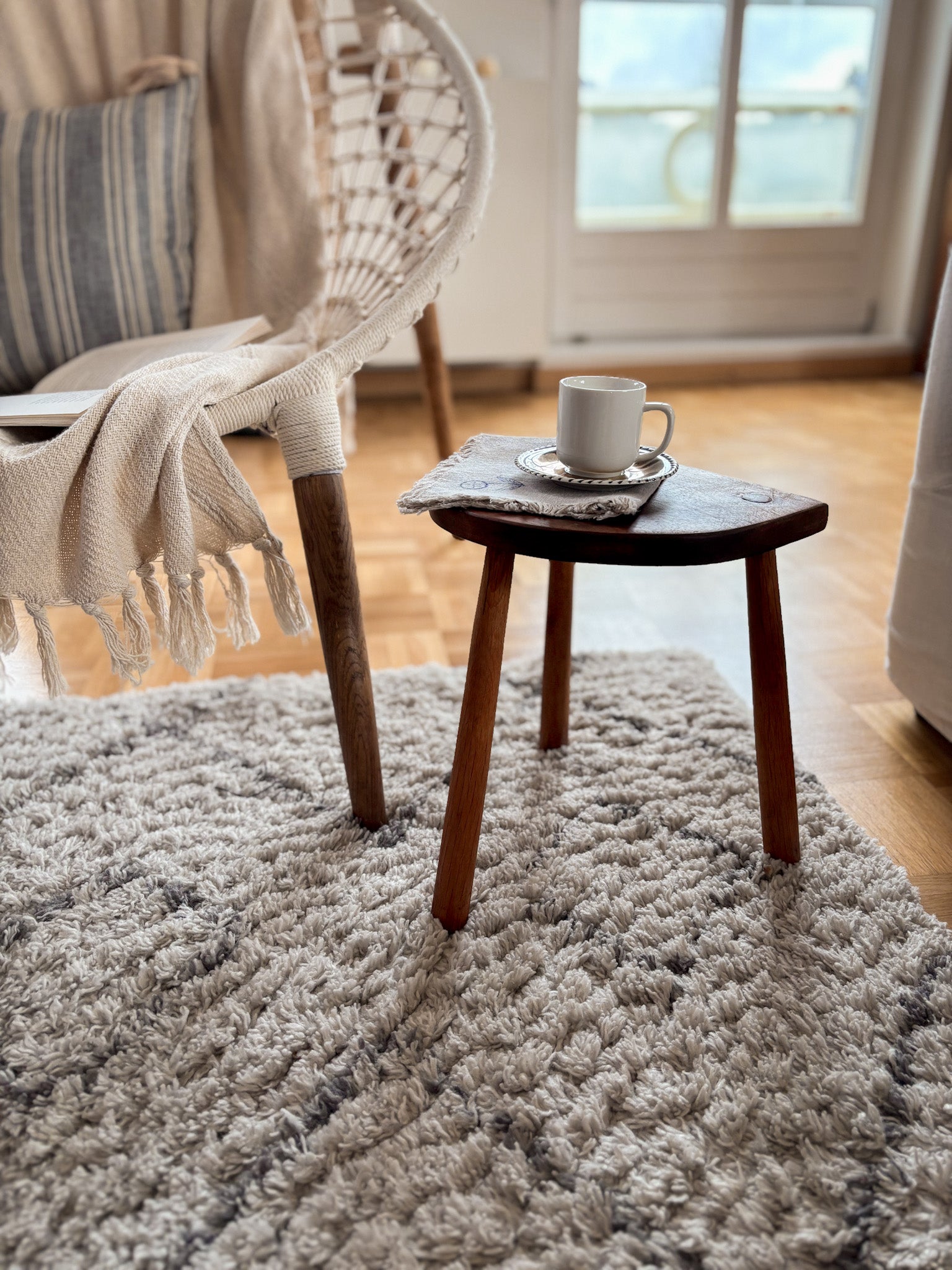 Cozy living room with a vintage french wooden stool, and coffee cup on a rug.